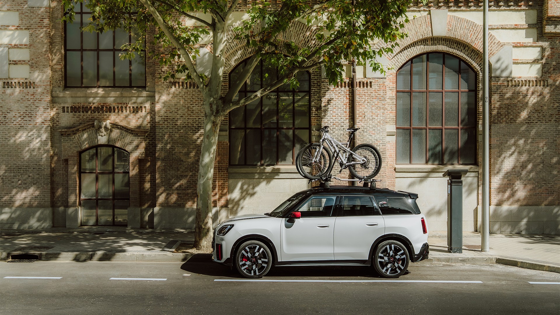 Vorderansicht des MINI Aceman in Indigo Sunset Blue mit MINI Fahrraddachträger mit Mountainbike und MINI Dachbox 320.